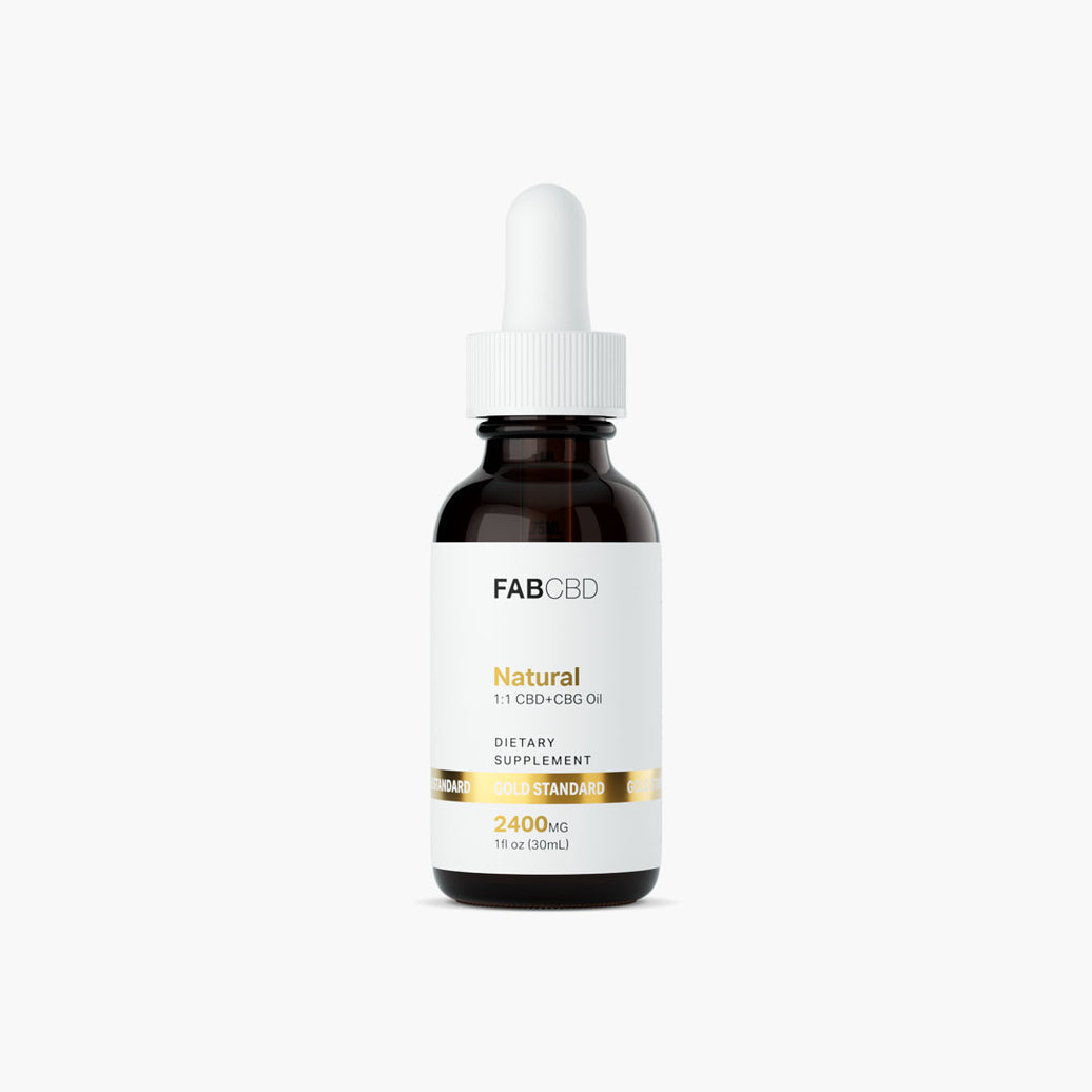 FABCBD Natural 1:1 CBD+CBG Oil dark amber glass bottle with a white dropper cap standing upright against a plain white background. The front white label displays a metallic gold ribbon reading "GOLD STANDARD" along with the product details: "DIETARY SUPPLEMENT", "2400MG", and "1 fl oz (30mL)."