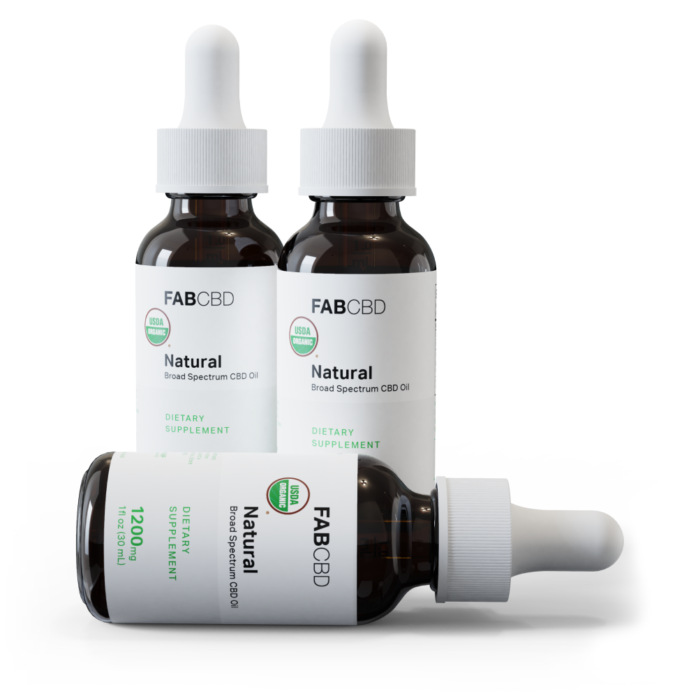 Three amber glass dropper bottles of FAB CBD 'Natural' Broad Spectrum CBD Oil with white caps and white labels featuring a green USDA Organic seal, two standing upright and one lying on its side showing '1200mg, 1 fl oz (30 mL), Dietary Supplement,' on a white background.