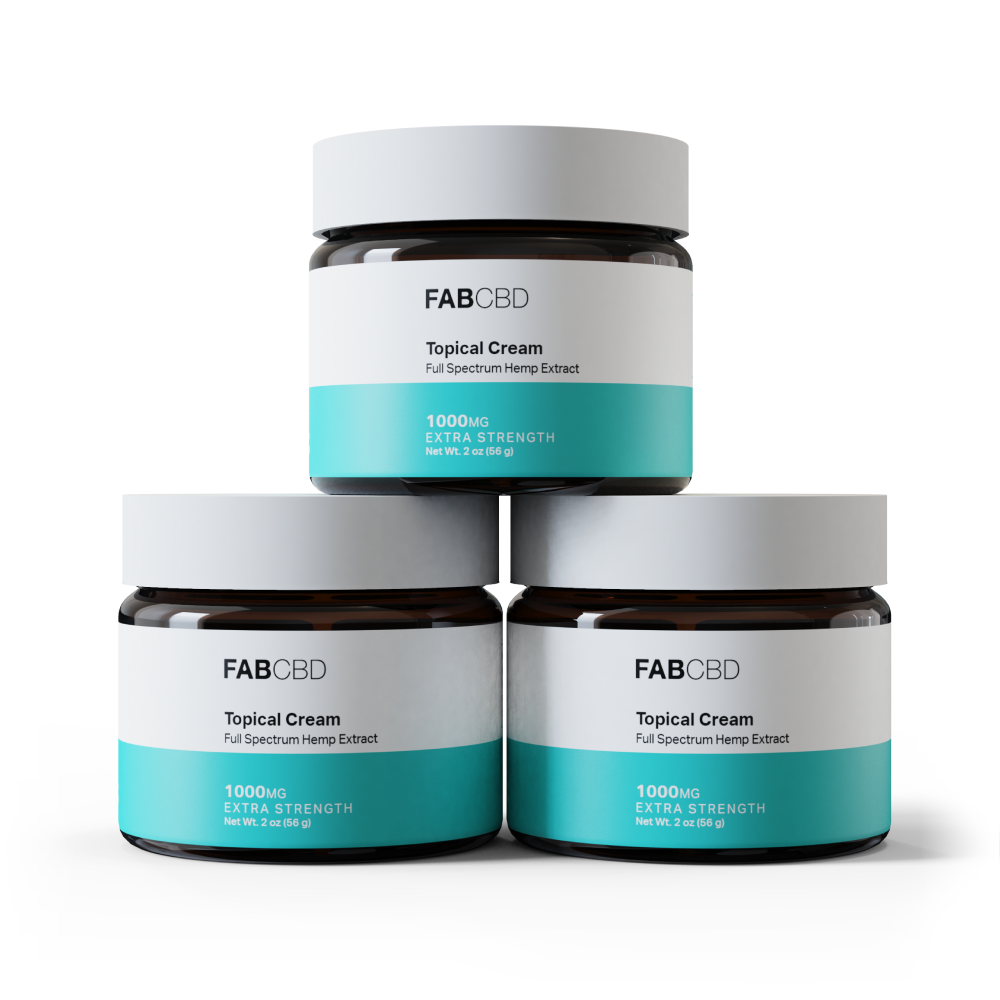 Three amber glass jars of FAB CBD Topical Cream with white lids, stacked in a pyramid arrangement, each featuring a white-and-teal label reading 'Full Spectrum Hemp Extract, 1000mg Extra Strength, Net Wt. 2 oz (56 g),' shown against a plain white background.