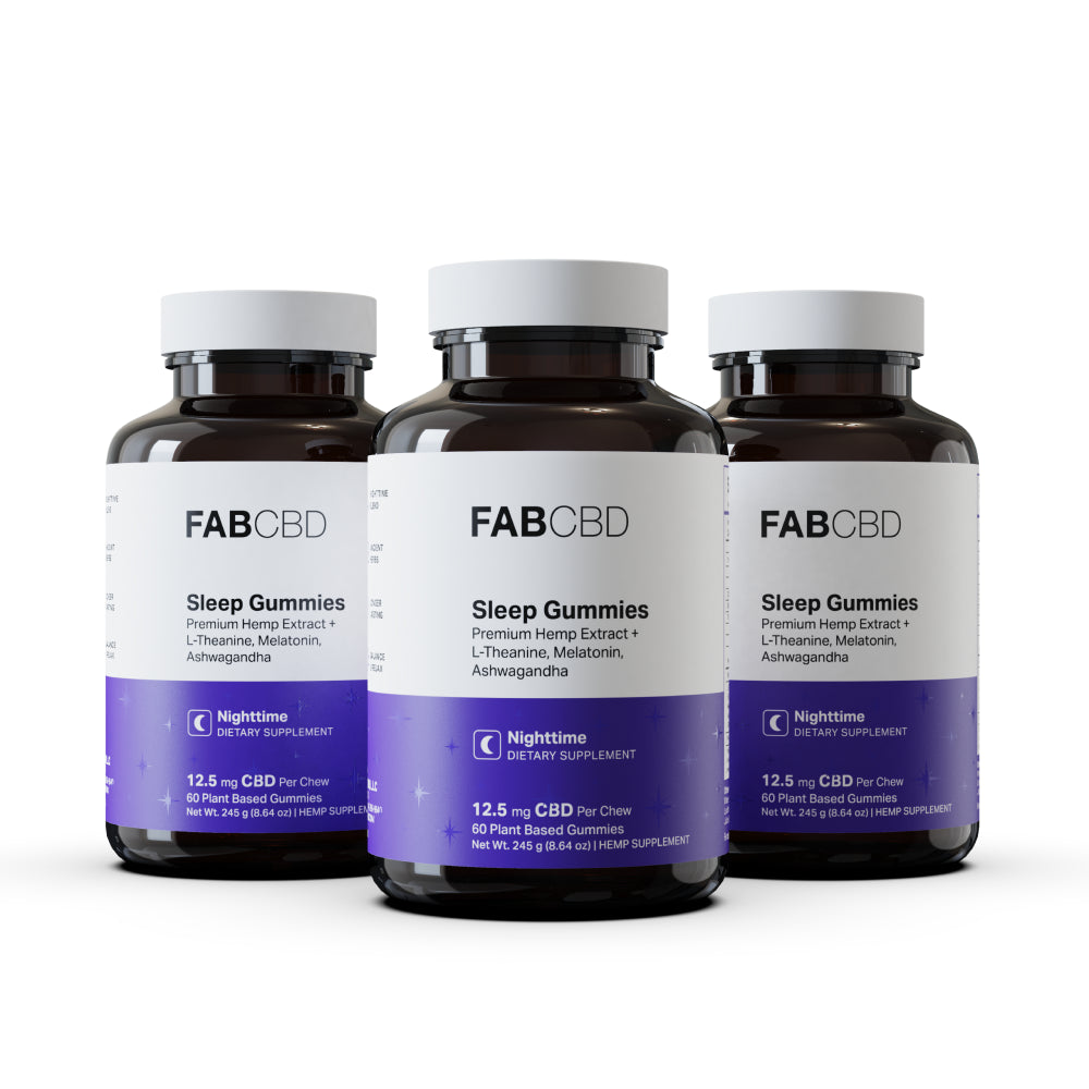 Three amber glass bottles of FAB CBD Sleep Gummies with white caps and purple labels featuring a crescent moon icon, reading 'Premium Hemp Extract + L-Theanine, Melatonin, Ashwagandha, Nighttime Dietary Supplement, 12.5 mg CBD Per Chew, 60 Plant Based Gummies, Net Wt. 245 g (8.64 oz),' arranged side by side on a white background.