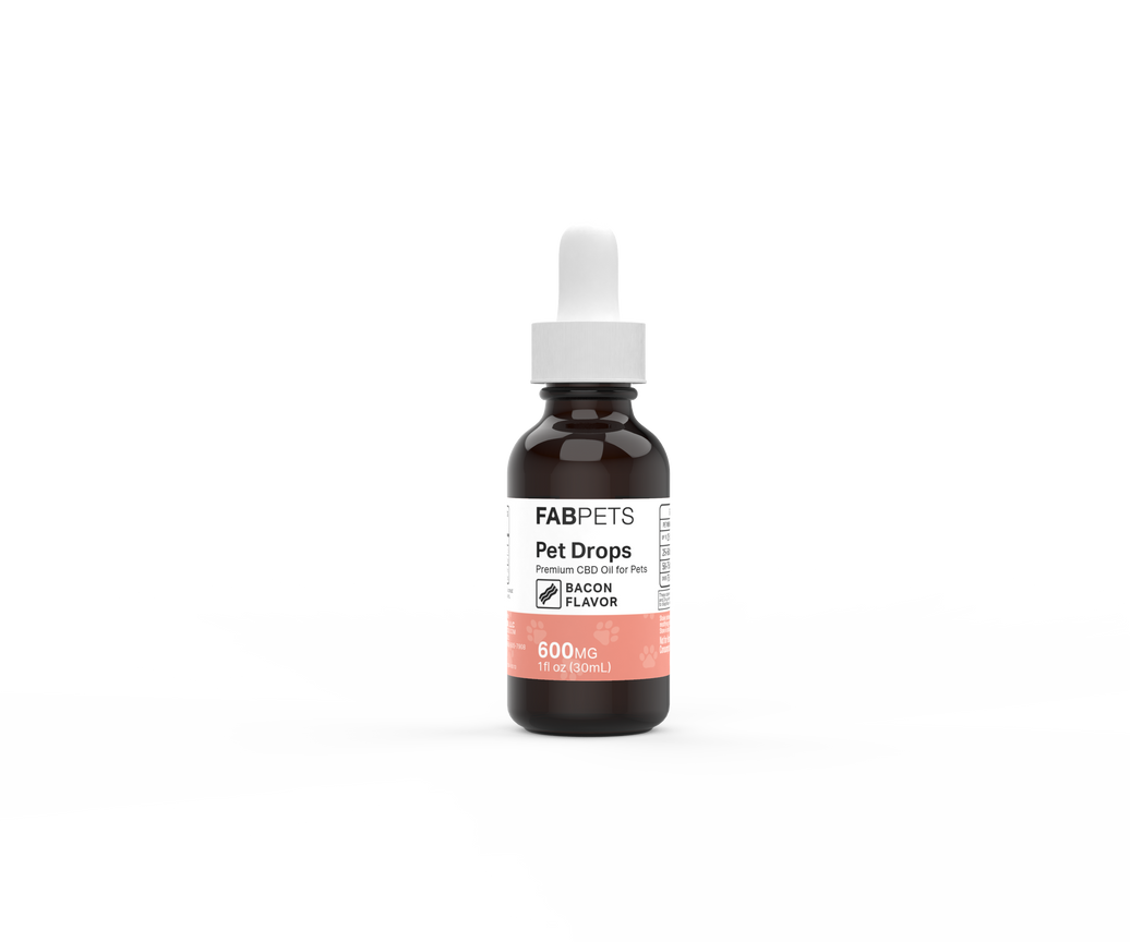 A dark amber glass bottle with a white dropper cap standing upright against a black and grey checkered background grid. The front label features FAB PETS branding for "Pet Drops" described as "Premium CBD Oil for Pets" with a "BACON FLAVOR" icon. The lower peach-colored section of the label displays the product specifications: "600MG" and "1 fl oz (30mL)."